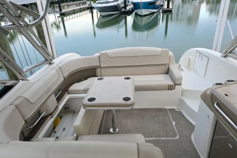 Slide: The Image of 2015 Formula 350 Crossover Bowrider I/O interior with seating and table, docked by calm water. - 7