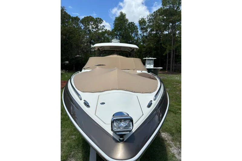 Slide: The Image of 2015 Formula 350 Crossover Bowrider I/O with tan cover, parked on grass. - 3