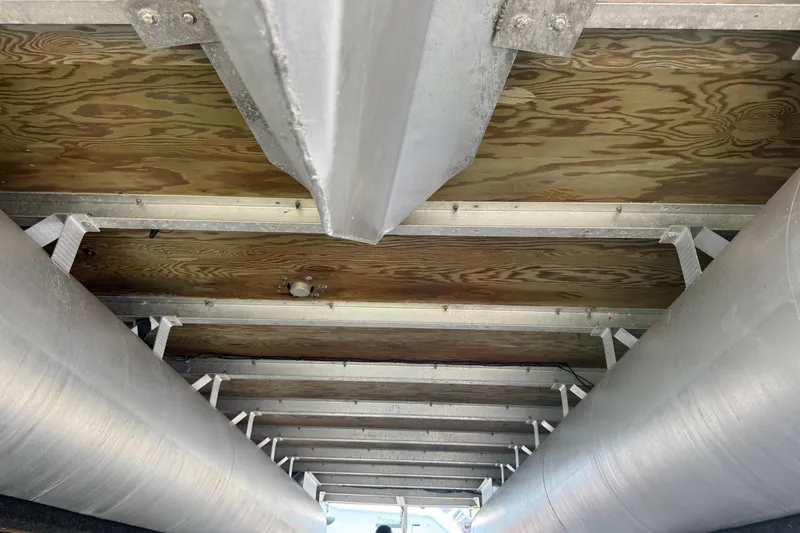 Slide: The Image of Underneath view of a 2007 Bennington 2574 GL pontoon boat, showcasing aluminum pontoons and wooden deck. - 42