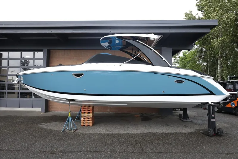 The Image of 2021 Cobalt R30 boat in blue, displayed on stands outside a garage. - 1