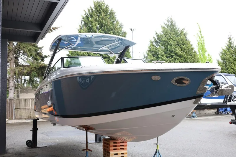 Slide: The Image of 2021 Cobalt R30 boat on display, elevated on blocks, surrounded by trees and structures. - 15