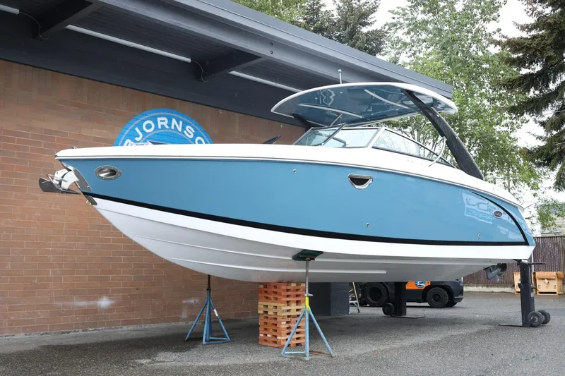 Slide: The Image of 2021 Cobalt R30 boat displayed on stands, blue and white exterior, outdoor setting. - 20