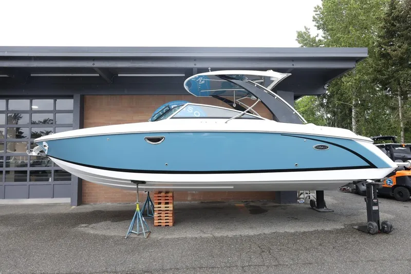 Slide: The Image of 2021 Cobalt R30 boat in blue, displayed on stands outside a garage. - 21