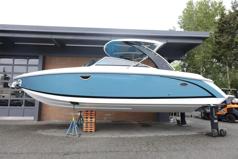 Slide: The Image of 2021 Cobalt R30 boat in blue, displayed on stands outside a garage. - 22