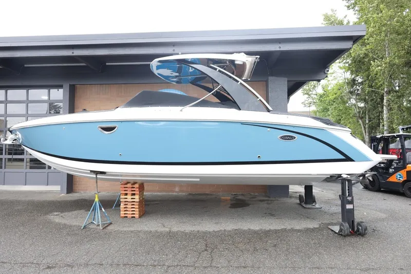 Slide: The Image of 2021 Cobalt R30 boat in blue, displayed on stands outside a garage. - 4