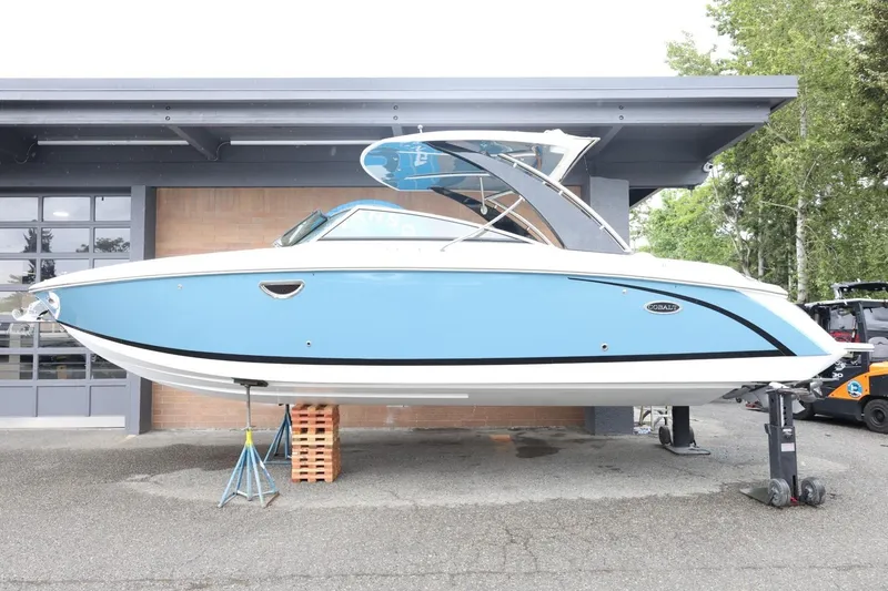 Slide: The Image of 2021 Cobalt R30 boat in blue and white, displayed on stands outdoors. - 5