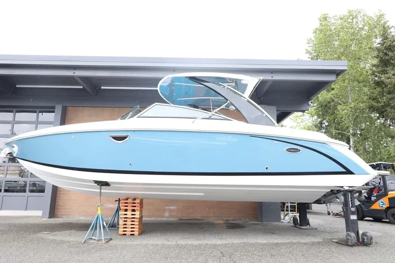 Slide: The Image of 2021 Cobalt R30 boat in blue, displayed on stands outside a building. - 6