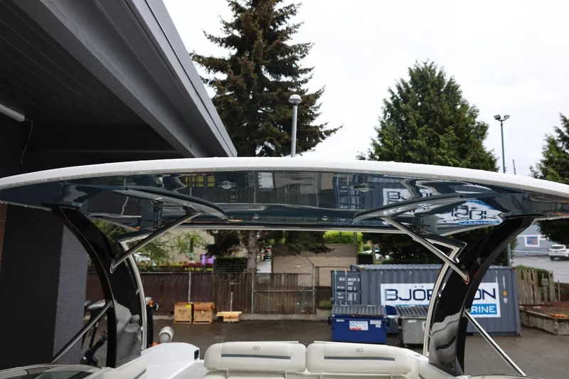 Slide: The Image of 2021 Cobalt R30 boat with sleek canopy design, parked outdoors near trees and containers. - 77