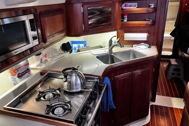 Slide: The Image of Compact kitchen in a 1996 Hunter 430 yacht with stove, sink, and wooden cabinetry. - 13