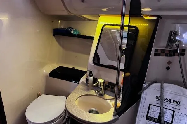 Slide: The Image of Compact bathroom in a 1996 Hunter 430 sailboat, featuring a sink, toilet, and mirror. - 8