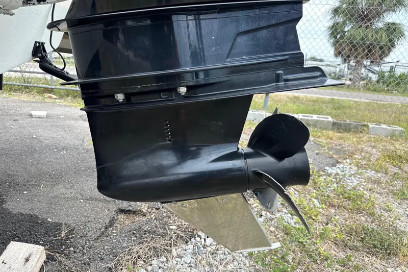 Slide: The Image of 2023 Scout 215 Dorado boat motor and propeller, parked on gravel near a fence. - 6