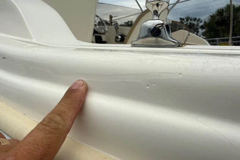 Slide: The Image of 2023 Scout 215 Dorado boat with visible surface imperfections and a finger pointing at them. - 8