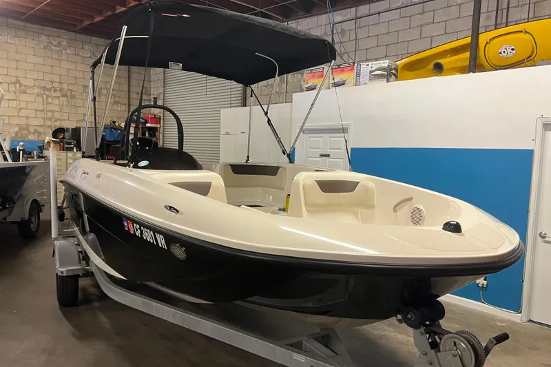 Slide: The Image of 2019 Bayliner Element E18 boat in a garage, featuring a sleek design and canopy. - 2