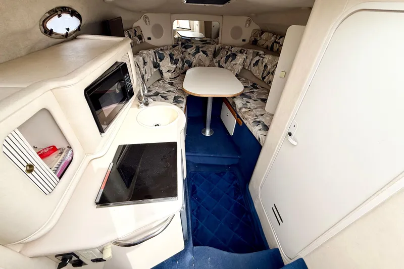 Slide: The Image of Interior of 1999 Sea Ray Sundancer 260, featuring kitchenette, seating area, and table. - 14