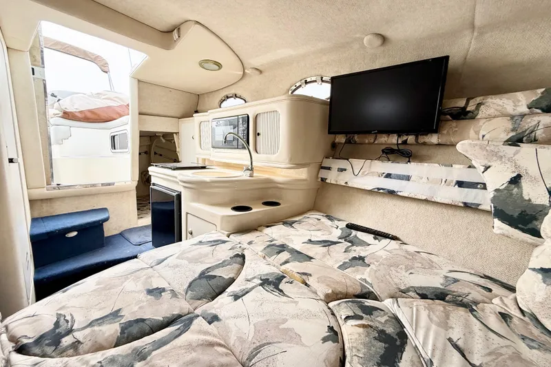 Slide: The Image of 1999 Sea Ray Sundancer 260 cabin interior with bed, kitchenette, and mounted TV. - 18