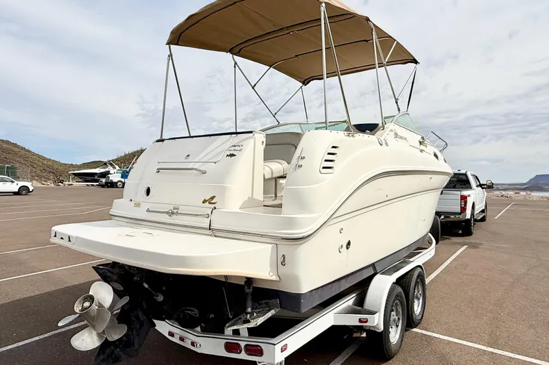 Slide: The Image of 1999 Sea Ray Sundancer 260 boat on trailer, parked in a lot under a cloudy sky. - 2