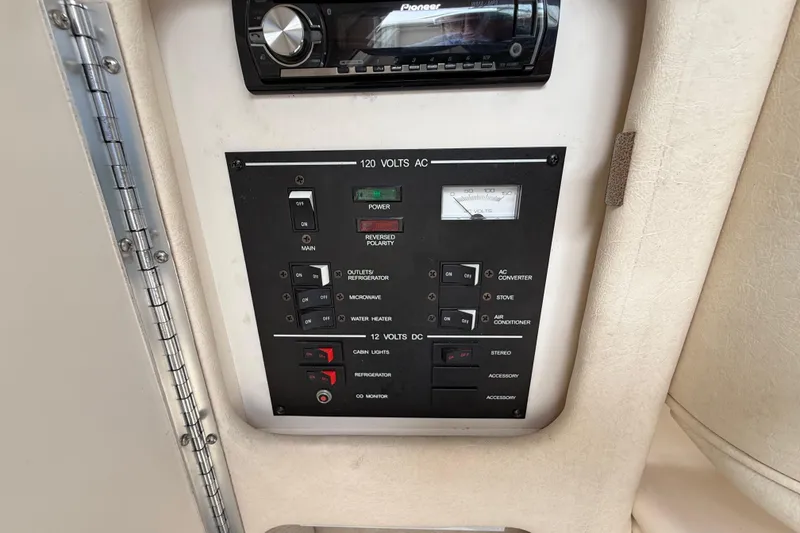 Slide: The Image of Control panel of a 1999 Sea Ray Sundancer 260 boat, featuring electrical switches and a stereo system. - 24