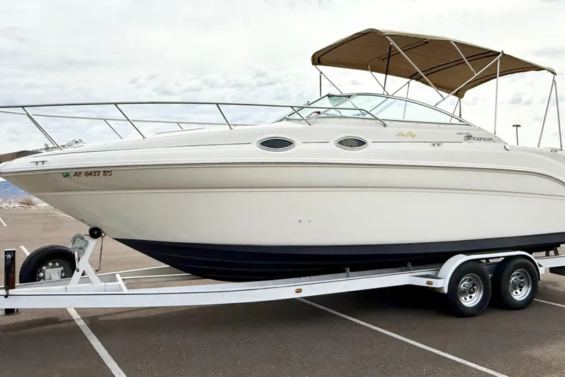 Slide: The Image of 1999 Sea Ray Sundancer 260 boat on trailer, parked in a lot under cloudy skies. - 34