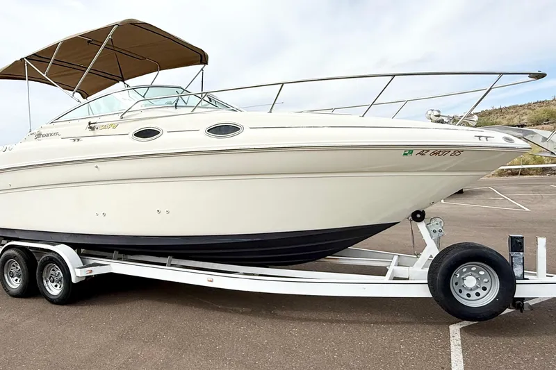 Slide: The Image of 1999 Sea Ray Sundancer 260 boat on trailer, featuring sleek design and beige canopy. - 35