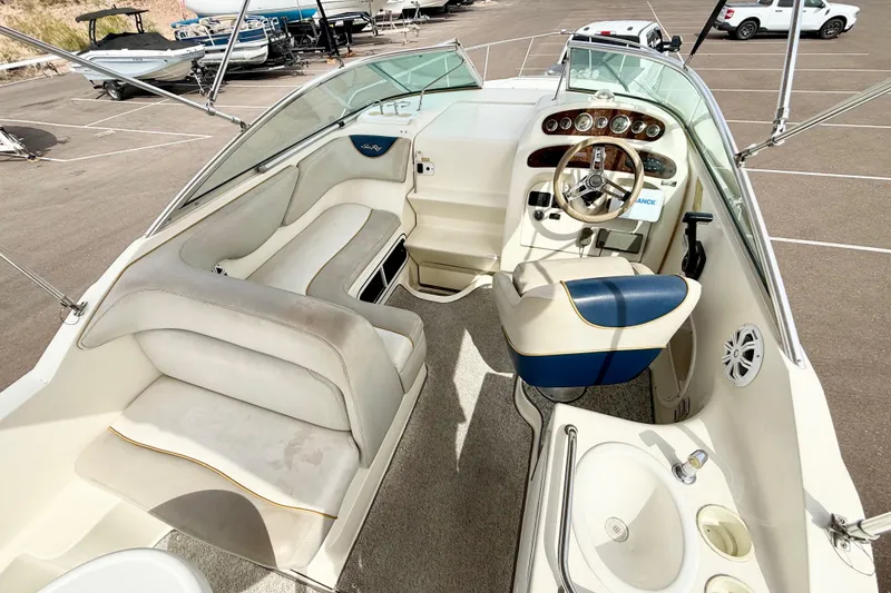 Slide: The Image of 1999 Sea Ray Sundancer 260 boat interior with steering wheel, seating, and sink in a parking lot. - 4