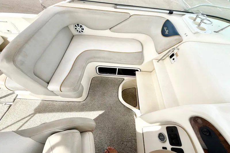 Slide: The Image of Interior seating of a 1999 Sea Ray Sundancer 260 boat, featuring plush upholstery and control panel. - 7