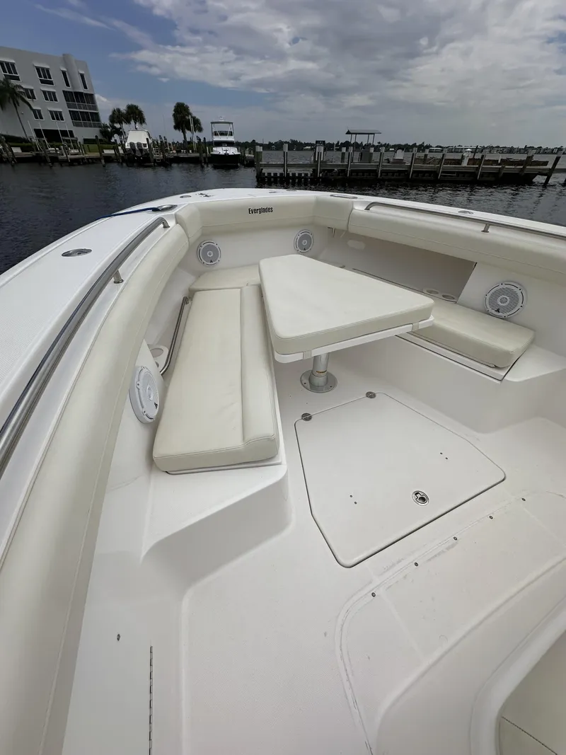 Slide: The Image of 2017 Everglades 435 Center Console boat with spacious seating and table, docked by the waterfront. - 22