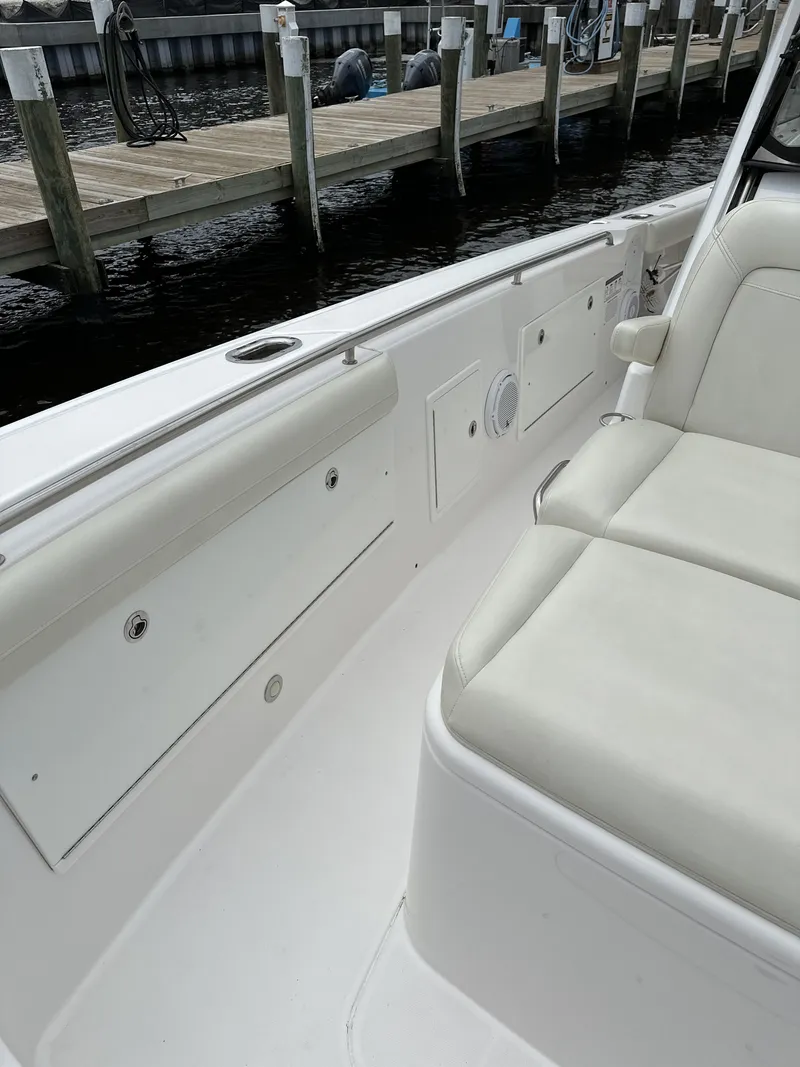 Slide: The Image of 2017 Everglades 435 Center Console boat interior with white seating and dockside view. - 28