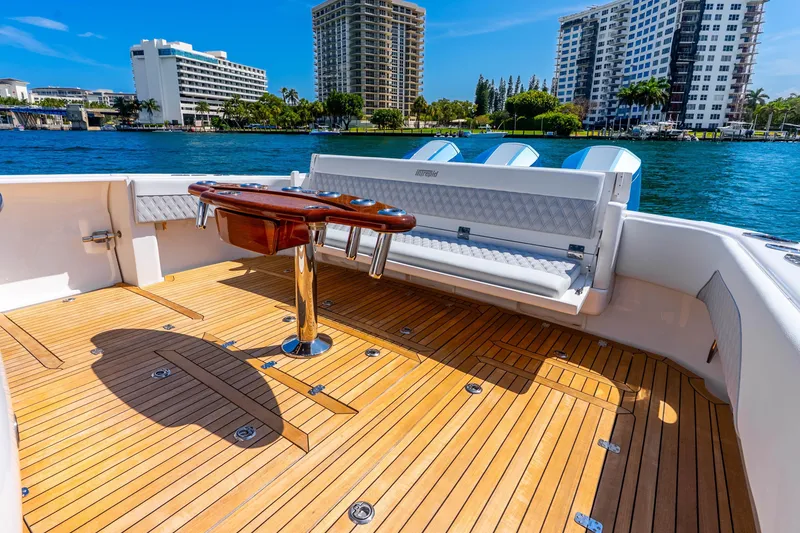 Slide: The Image of 2015 Intrepid 475 Panacea boat deck with wooden flooring and seating, docked near waterfront buildings. - 29