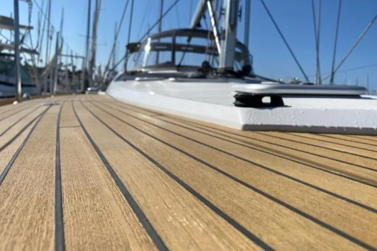 Slide: The Image of 2013 Jeanneau 57 yacht deck with sleek wooden finish and clear blue sky. - 12