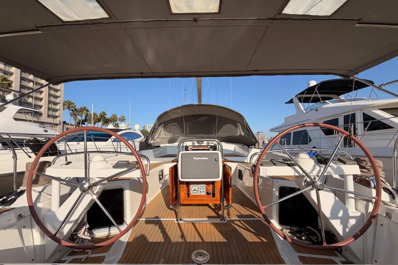 Slide: The Image of 2013 Jeanneau 57 yacht cockpit with dual steering wheels, docked in a marina. - 16