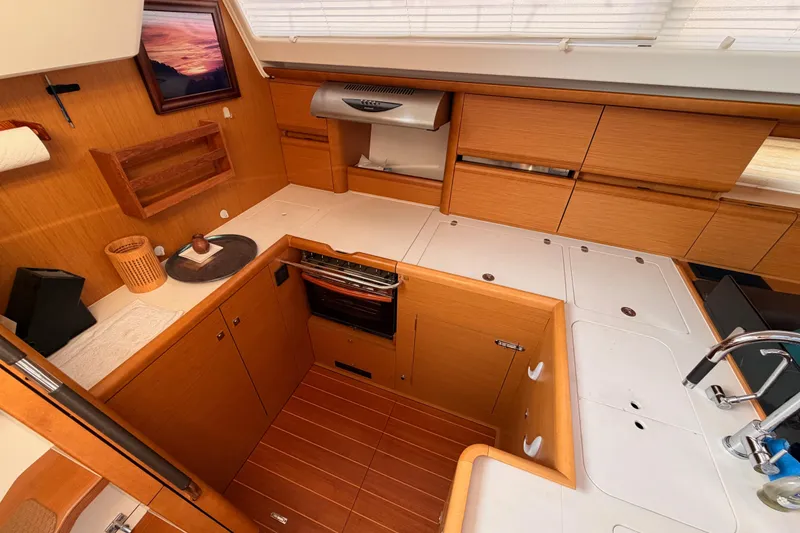 Slide: The Image of Luxurious 2013 Jeanneau 57 yacht kitchen with wood cabinetry and modern appliances. - 30