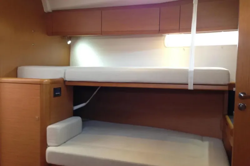 Slide: The Image of Interior of 2013 Jeanneau 57 yacht with wooden bunk beds and storage cabinets. - 44