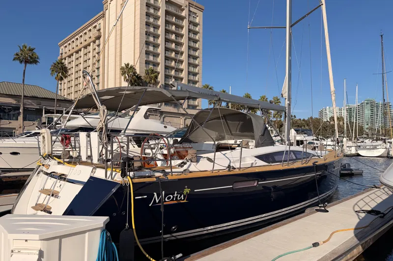 Slide: The Image of 2013 Jeanneau 57 yacht docked at marina with cityscape background. - 5