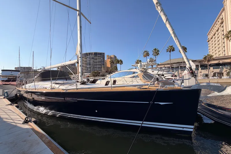 Slide: The Image of 2013 Jeanneau 57 yacht docked in a marina with palm trees and buildings. - 6