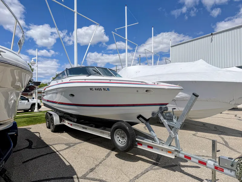 Slide: The Image of A white sport boat on a trailer, surrounded by other boats, under a blue sky. - 1