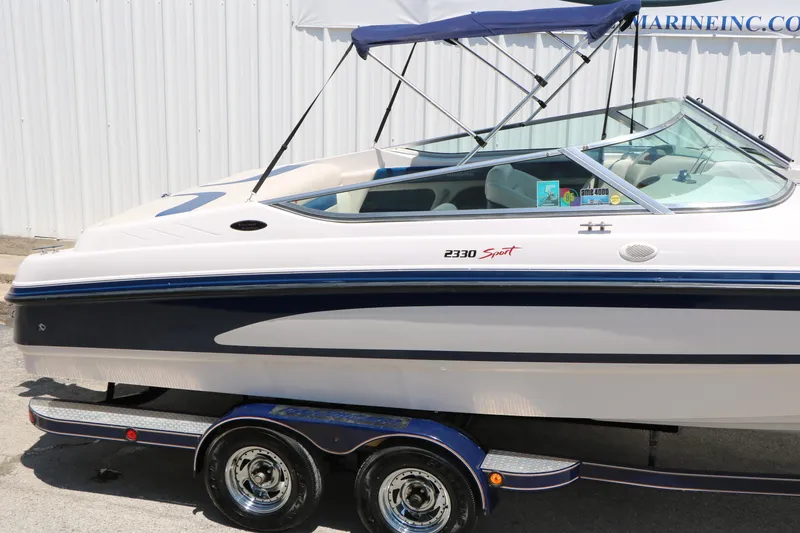Slide: The Image of 1996 Chaparral 2330 SS boat with blue accents and trailer, parked outdoors. - 12