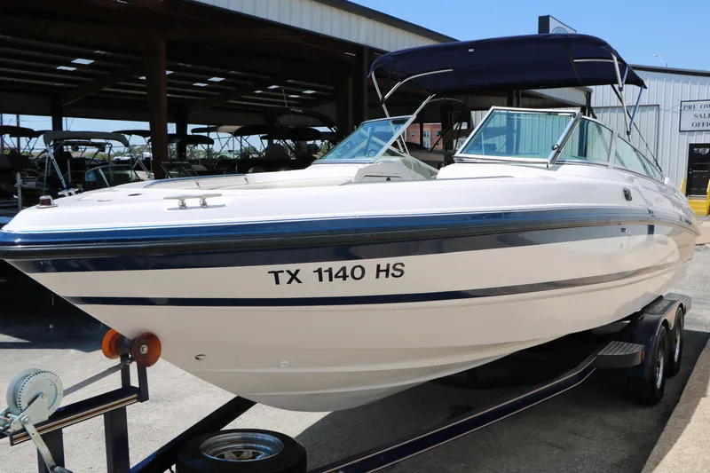 Slide: The Image of 1996 Chaparral 2330 SS boat on trailer with blue canopy in storage facility. - 4