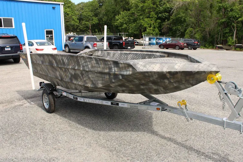 Slide: The Image of 2026 WeldBilt 1660V boat on trailer in front of blue building. - 5