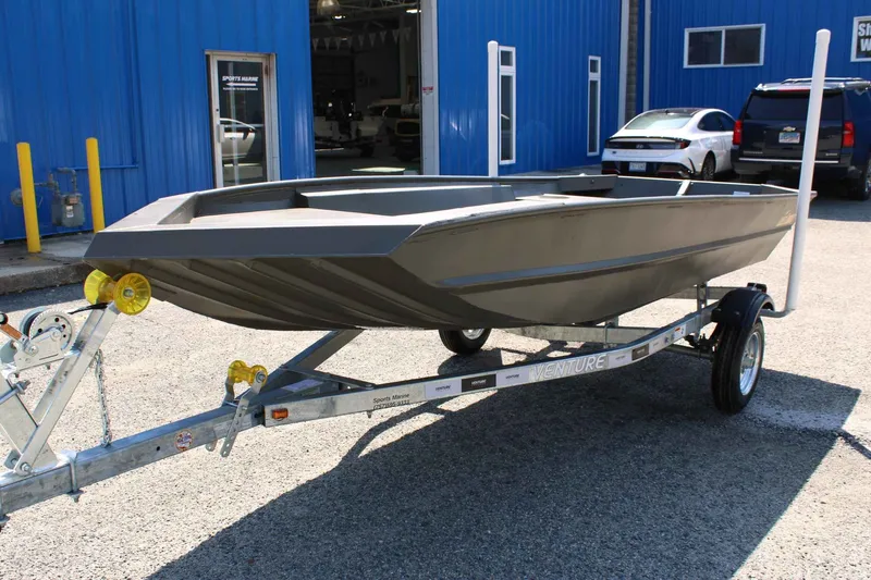 Slide: The Image of WeldBilt 1448V 2026 aluminum boat on trailer outside blue workshop. - 7
