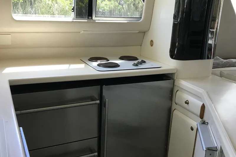 Slide: The Image of Compact kitchen area in a 1995 Sea Ray 550 Sedan Bridge yacht, featuring a stovetop and storage. - 19