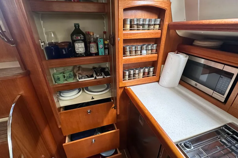 Slide: The Image of Compact kitchen in 2003 Hunter 426 Deck Salon with spices, microwave, and storage. - 35