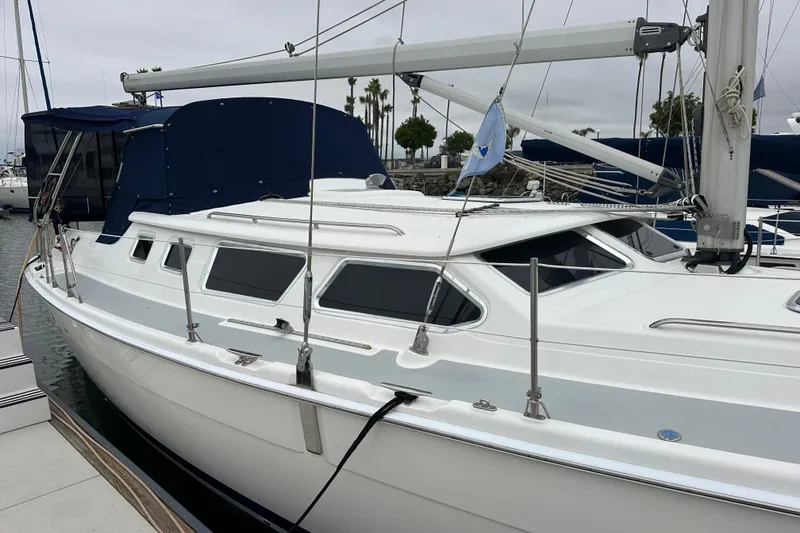 Slide: The Image of 2003 Hunter 426 Deck Salon sailboat docked at marina, featuring sleek design and blue canopy. - 4