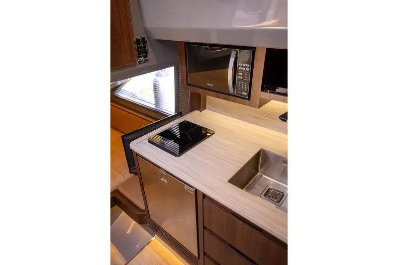 Slide: The Image of Modern kitchen in 2027 Hanover 447 RV with microwave, induction cooktop, and stainless steel sink. - 7