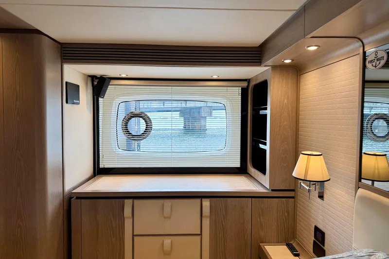 Slide: The Image of Interior of 2020 Azimut Magellano 66 yacht, featuring elegant wood finishes and a porthole window. - 54