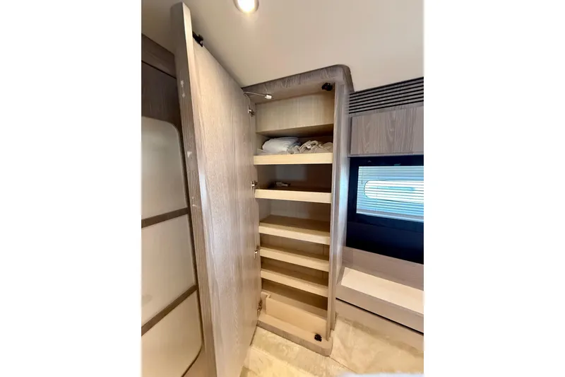 Slide: The Image of Open wooden cabinet with shelves inside Azimut Magellano 66 yacht, 2020 model. - 69