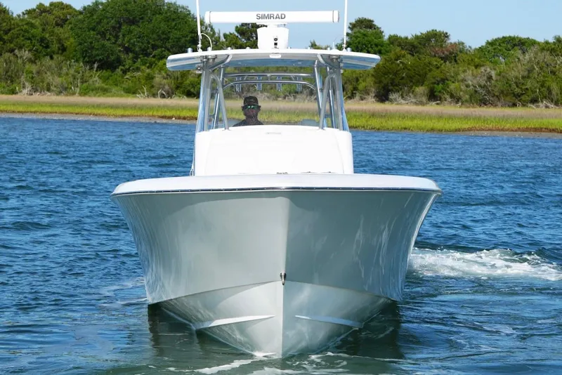 Slide: The Image of 2021 Contender 39 Fisharound boat cruising on a calm lake with lush greenery. - 5