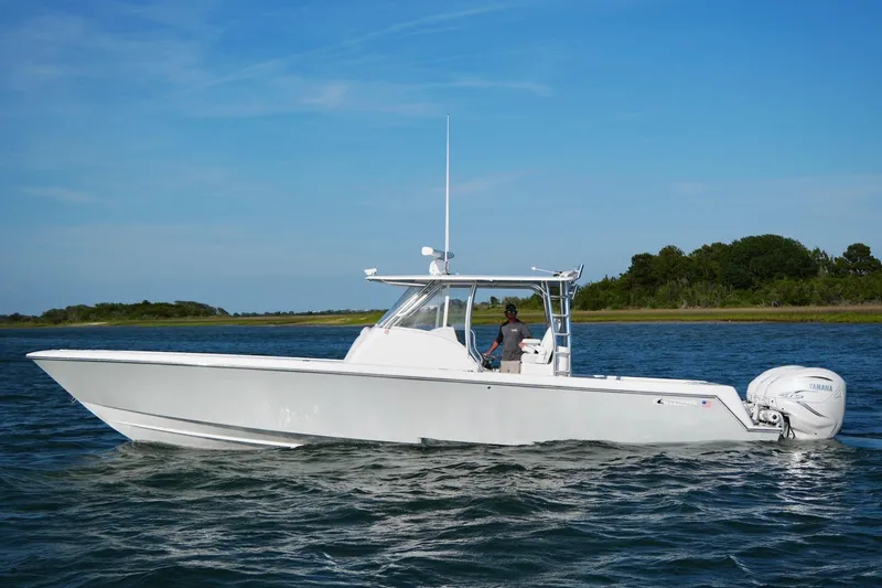 Slide: The Image of 2021 Contender 39 Fisharound boat cruising on a calm lake under a clear blue sky. - 9