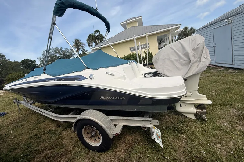 The Image of 2020 Hurricane SunDeck Sport 185 OB boat on trailer, covered and parked outdoors. - 0