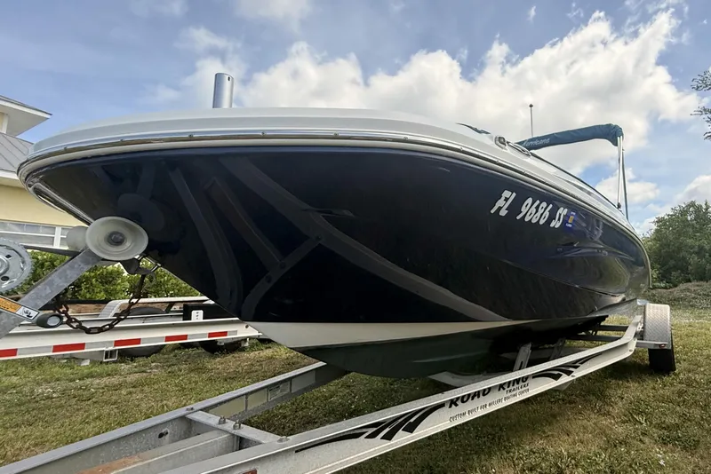 Slide: The Image of 2020 Hurricane SunDeck Sport 185 OB boat on trailer, parked outdoors under a cloudy sky. - 2