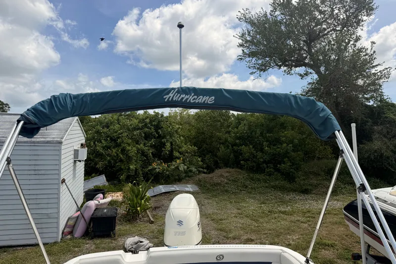 Slide: The Image of 2020 Hurricane SunDeck Sport 185 OB boat with canopy, parked outdoors under a cloudy sky. - 5